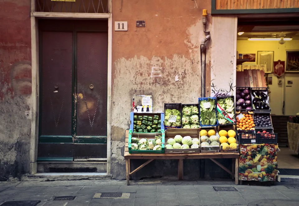 Crates of fresh vegetables and fruit set out on a table in front of a small shop