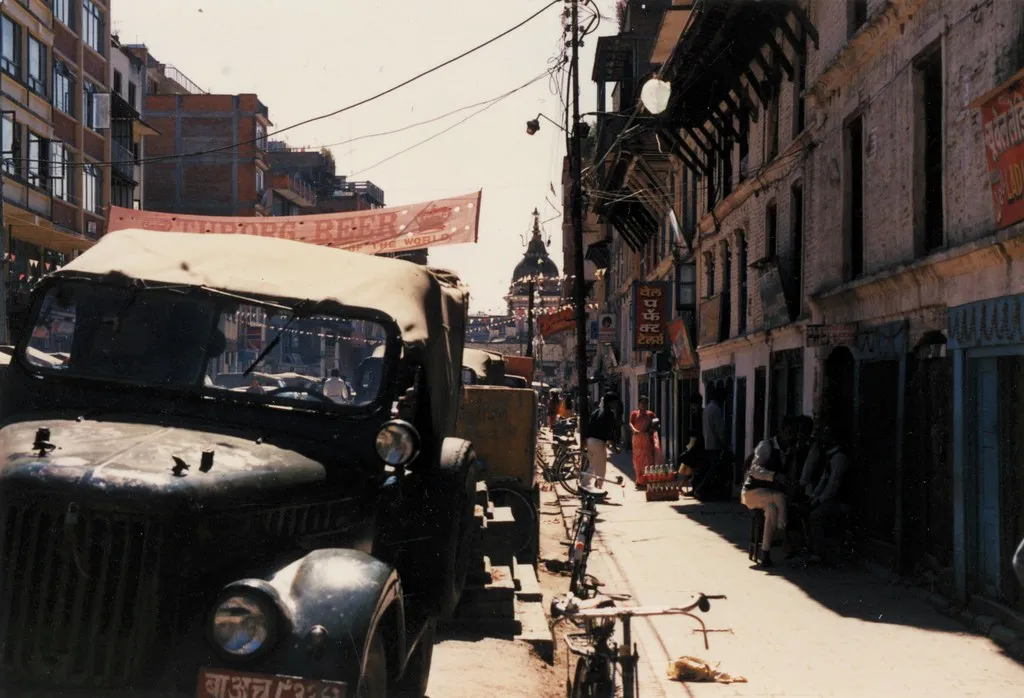 A narrow shopping street with small shopfronts, bicycles and an old truck